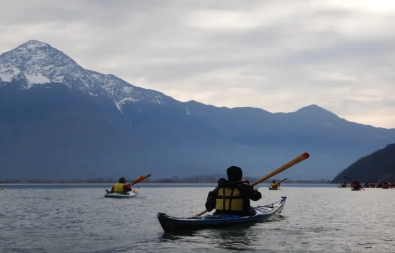 23° Cimento Invernale sull’Alto Lario – 4-5 Febbraio 2022 23° Cimento Invernale sull’Alto Lario, 4-5 Febbraio 2022: kayaker in navigazione sul lago davanti alle montagne innevate