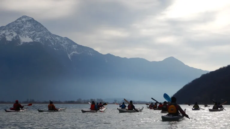 23° Cimento Invernale sull’Alto Lario – 4-5 Febbraio 2022 23° Cimento Invernale sull’Alto Lario, 4-5 Febbraio 2022: gruppo di kayak sul lago sotto le montagne innevate