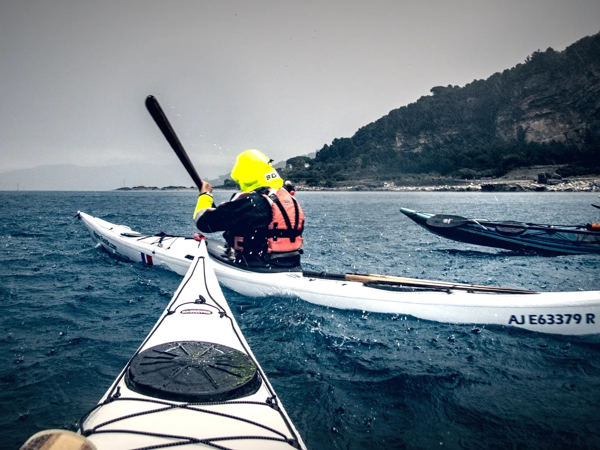 Esame Pagaia Azzurra: pagaiatore con giacca impermeabile e aiuto al galleggiamento sul mare mosso, visto da un altro kayak