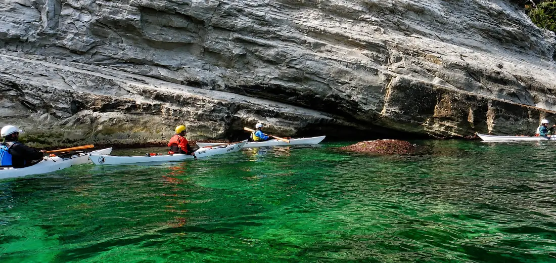 Formazione e certificazioni di kayak da mare: kayak sull'acqua verde sotto la scogliera
