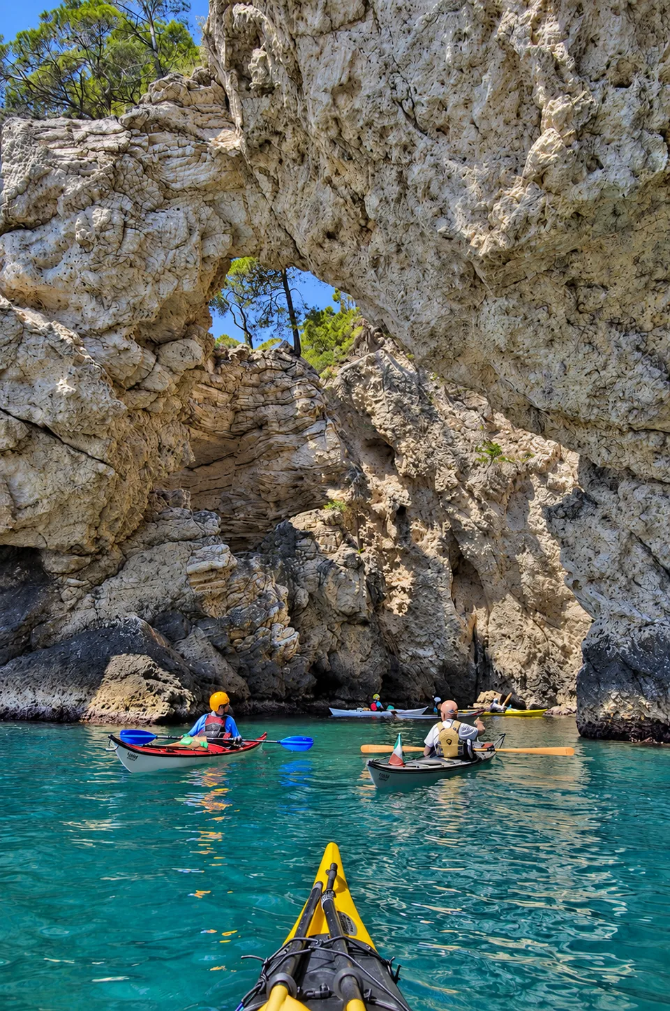 Il kayak da mare: gruppo di kayak da mare in acqua turchese davanti a un arco di roccia