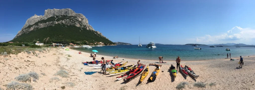 Briefing Sardegna Camp 2018: kayak sulla spiaggia di una baia con l'isola sullo sfondo