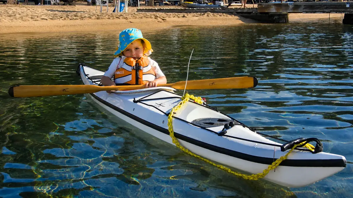 Formazione e certificazioni di kayak da mare: bambino con il giubbotto salvagente seduto nel kayak