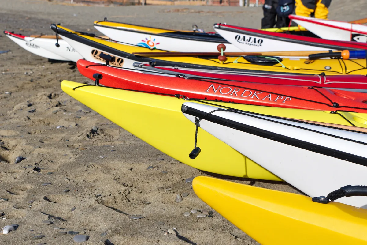 Il kayak da mare: prue di kayak da mare allineate sulla spiaggia, con le cime di sicurezza in coperta