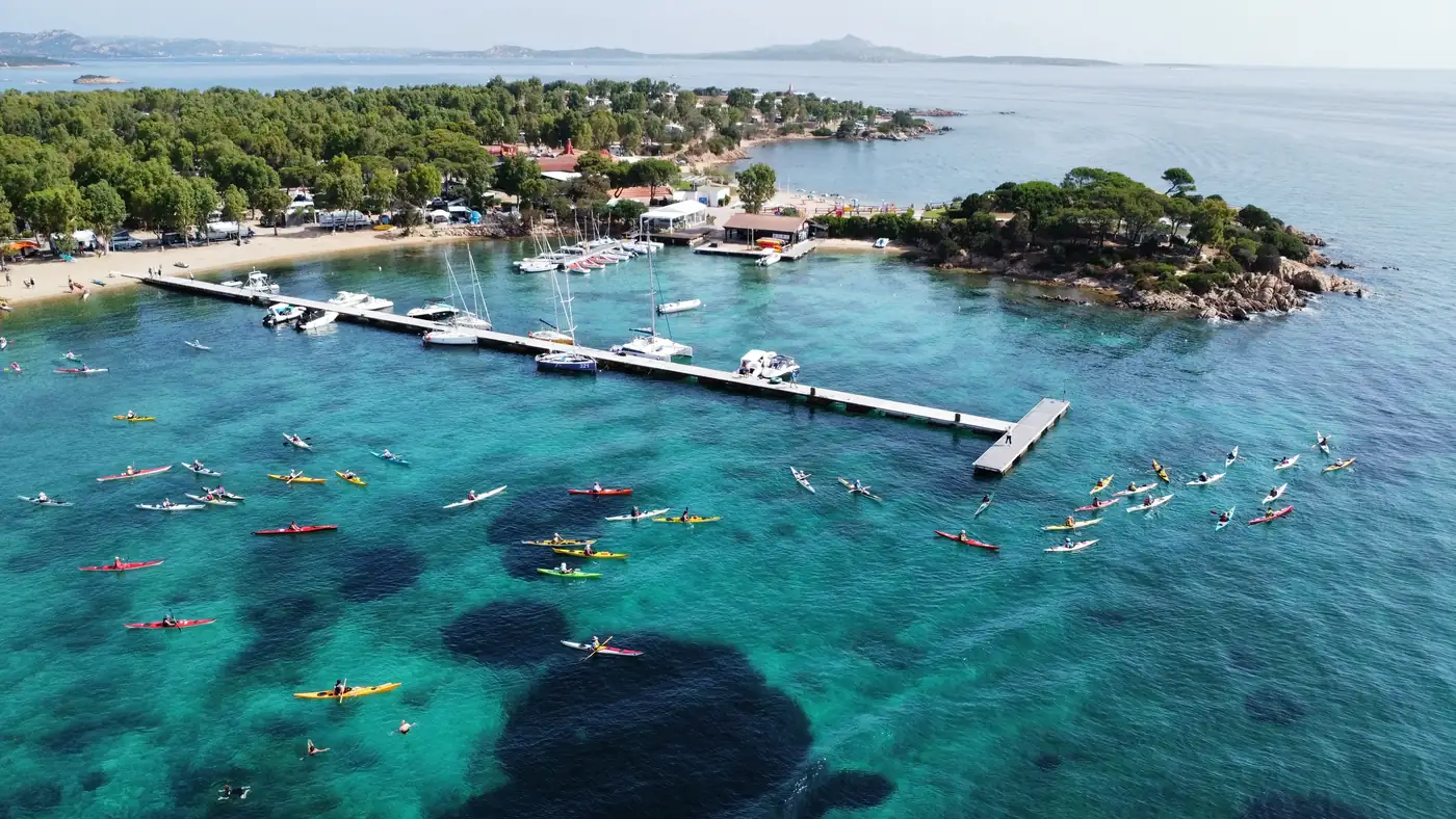 Tesseramento a Sottocosta: raduno di kayak da mare visto dall’alto, con i kayak in acqua davanti al molo