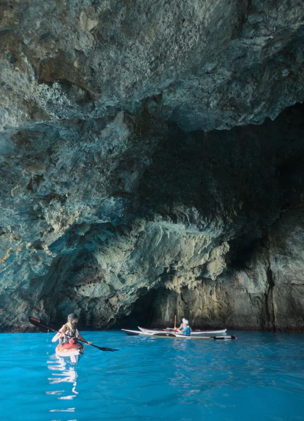 Storia e regole del kayak da mare: due kayak all’ingresso di una grotta marina, nell’acqua turchese
