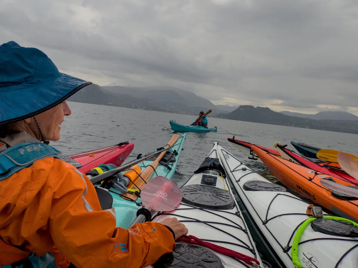 Scegliere un kayak da mare: kayak di modelli e colori diversi affiancati in acqua, durante un’uscita di gruppo