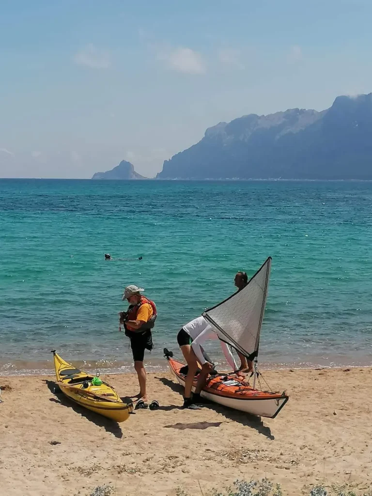 Sottocosta Camp 2022 a Calacavallo (Sardegna): kayaker che preparano i kayak a vela sulla spiaggia